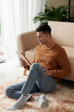 Adam tablet bilgisayardan filmi izliyor.