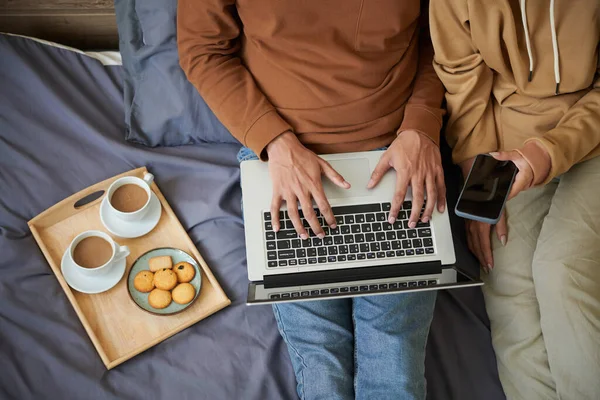 Pareja que conecta el portátil con el teléfono móvil — Foto de Stock