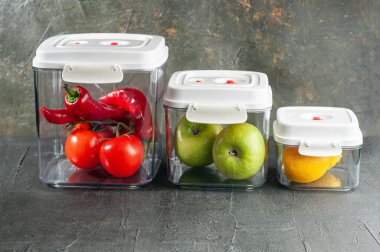 Pompalı ve vanalı vakum kapları. Yiyecek deposu için. Üç kişilik bir set. Kare şeklinde. Yiyecek kalitesinde plastik malzeme. Koyu arkaplan.