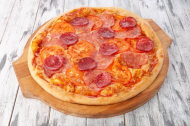 Jambonlu pizza, salam, domates sosu ve mozzarella peyniri. Yuvarlak tahta. Hafif ahşap zemin. Yukarıdan görüntüle.