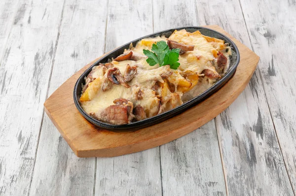 Mantar ve patatesli domuz eti. Peynir sosu ve kremayla pişirilmiş. Kızartma tavasında. Hafif ahşap zemin. Yukarıdan görüntüle.