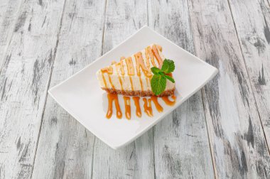 Klasik New York peynirli keki. Karamel kaplamalı. Beyaz bir tabakta. Hafif ahşap zemin. Yukarıdan görüntüle.