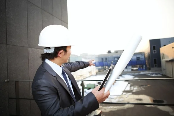 Arkitekt tittar och pekar buiding konstruktion — Stockfoto