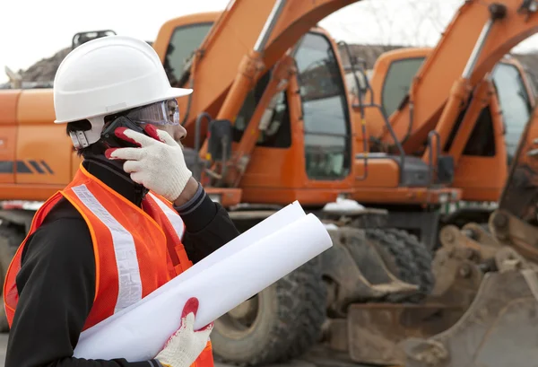 Trabajador de la construcción con planos de construcción y teléfono celular —  Fotos de Stock