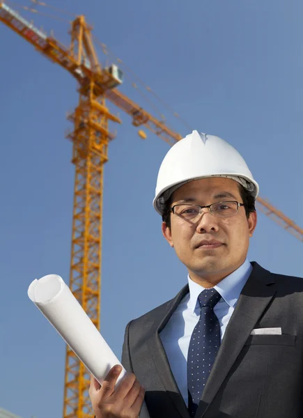 Young architect standing under yellow crane building site — Stock Photo, Image