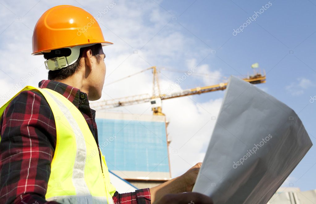 Builder with blueprint at construction site