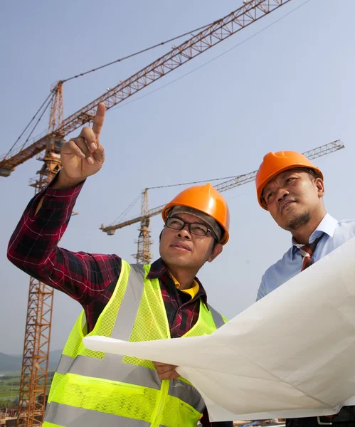 Unga asiatiska arkitekter diskussion framsidan av byggarbetsplats — Stockfoto