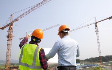 Site Yöneticisi ve inşaat işçisi planları kontrol