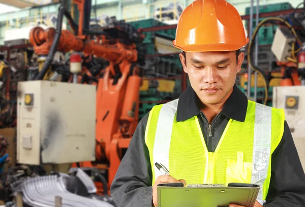 Asian civil engineer writing on notepad standing front of robot machine — Stock Photo, Image