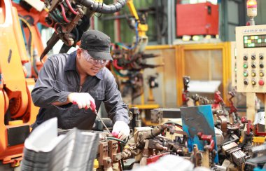 asian mechanical engineer working for maintenance or repairing robotic  machine in factory