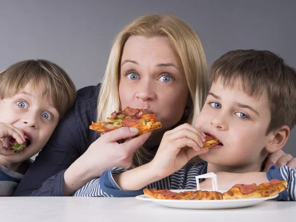 Familia hambrienta, madre e hijo comiendo pizza, el niño más joven prefiere las fresas —  Fotos de Stock