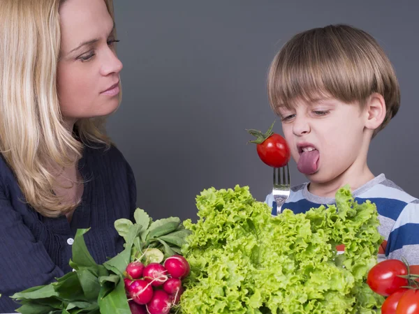 Mãe tentando alimentar seu filhinho que odeia comer tomate — Fotografia de Stock