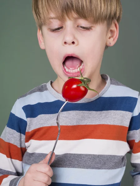 Niedliches Kind hält Tomate auf Gabel — Stockfoto