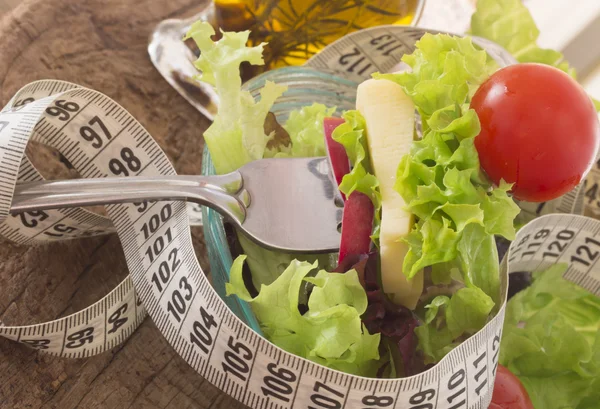 Salada fresca e saudável, rodeada por fita métrica — Fotografia de Stock