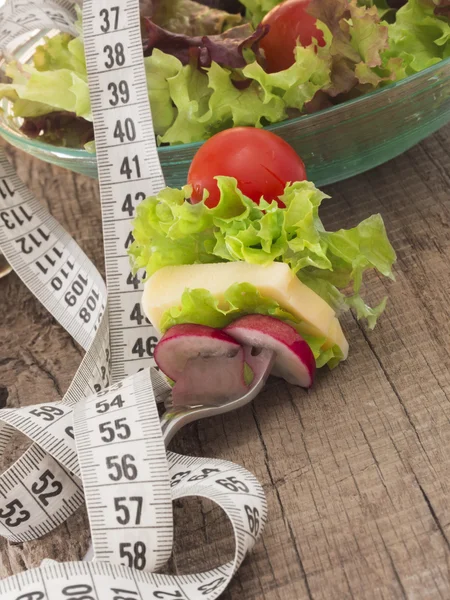 Frischer und gesunder Salat, umgeben von Maßband — Stockfoto