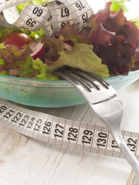 Salada fresca e saudável, rodeada por fita métrica — Fotografia de Stock