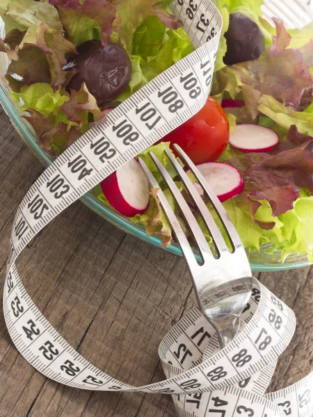 Frischer und gesunder Salat, umgeben von Maßband — Stockfoto