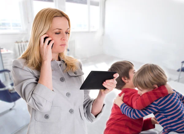 Busy mother with tablet and mobile while her children fighting — Stock Photo, Image