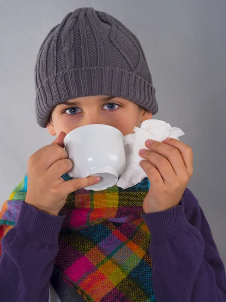 Boy drinking tea and wiping his nose — Stock Photo, Image