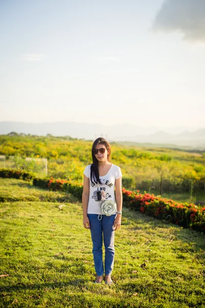 Donna in piedi sul campo di erba con la luce del sole sullo sfondo — Foto Stock