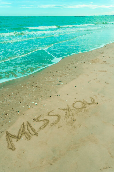 missyou written in sand on a beach