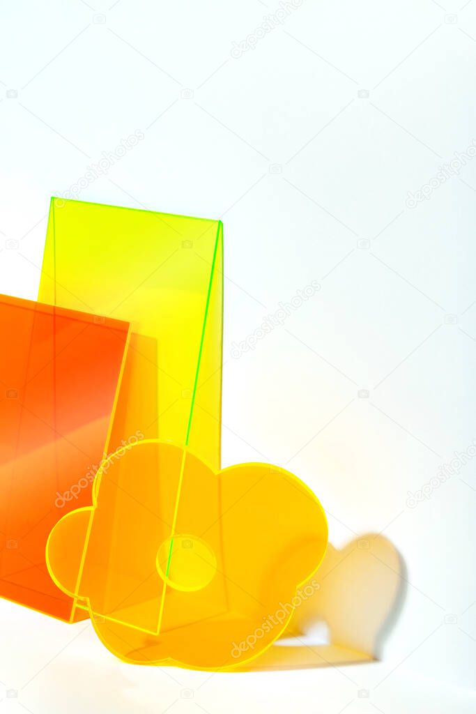 Funny yellow orange various acrylic shapes on a bright lit white background. Stylish abstract backdrop with space for text. Colourful stage for advertising, promoting, exhibition new products. 
