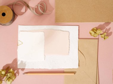 Zarf seti, defter, pembe arka planda kalem olan boş el yapımı kağıt kart. Gölgeli, eski moda model. Liste yapmak, tebrik kartı yazmak ya da mektup yazmak.