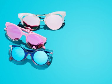 Minimalist yaz arkaplanı, mavi, kırmızı ve pembe retro şekilli güneş gözlükleri. İlkbahar mevsiminin modaya uygun ve modaya uygun UV koruması fikri. Göz koruma kavramı.