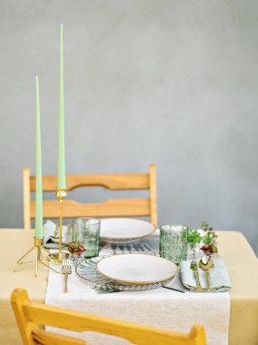 Romantik yemek için iki kişilik masa servis edildi. Mumlarla, keten peçetelerle, altın çatal bıçaklarla ve çiçeklerle dolu güzel, basit bir masa. Açık hava randevusu ya da düğün. Metin için alanı olan arkaplan.