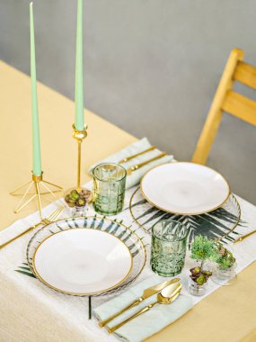 Beautiful simple table setting with linen napkins, gold cutlery and floristic. Table served for romantic dinner or festive event. Outdoor catering and dining.