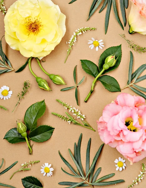 Flowers flat composition. Pattern made of summer garden flowers, buds, leaves and branches on beige background. Flat lay, top view.