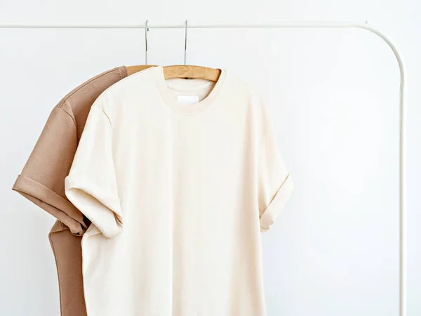 Deux Shirts Aux Couleurs Laiteuses Neutres Suspendus Sur Support Blanc — Photo