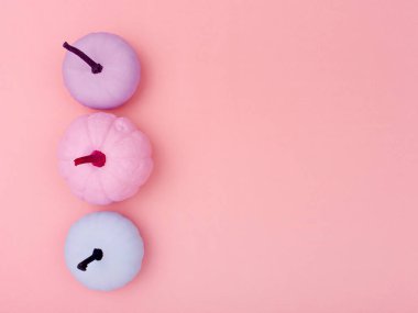 Creative autumn background. Top view of hand-painted various colours pumpkins on pink background. Autumn decorative stuff. Minimalist style Fall or Thanksgiving decorative border, frame.