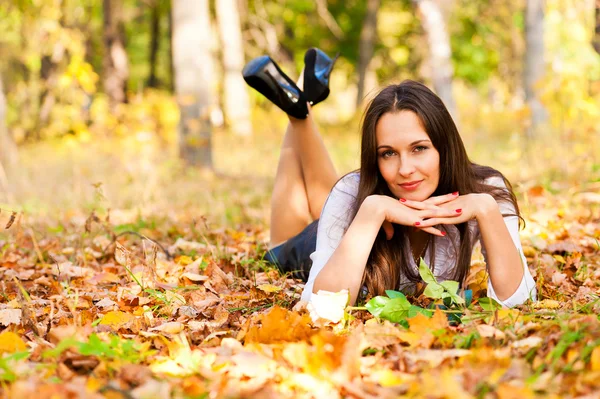 Güzel bir kadın yalan sonbahar yaprakları — Stok fotoğraf