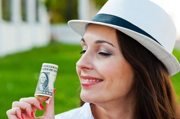 Mujer sonriente sosteniendo un dólar doblado —  Fotos de Stock