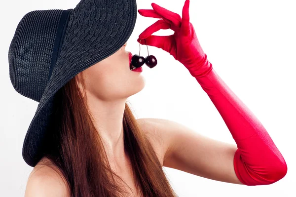 Mujer con sombrero y guantes comiendo cerezas — Foto de Stock