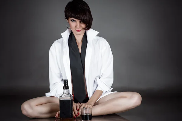 Woman sitting with a bottle of whiskey — Stock Photo, Image