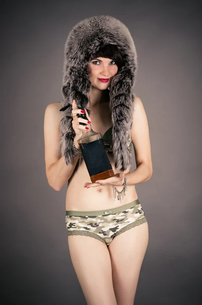 Frau mit Pelzmütze und einer Flasche Whiskey — Stockfoto