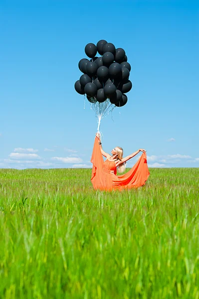 Kvinna i röd klänning med svarta ballonger — Stockfoto