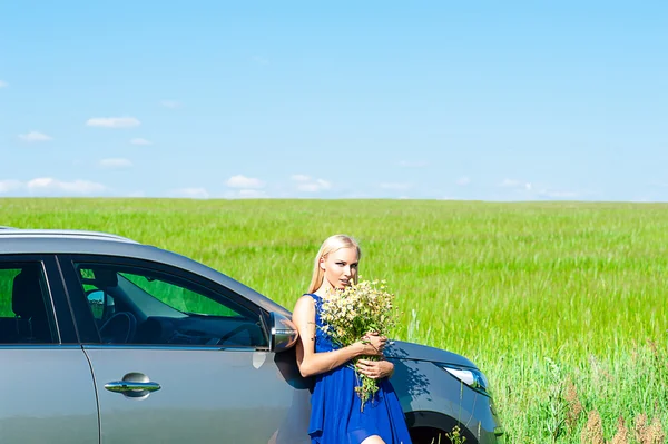 Femme avec des marguerites dans les mains debout près de la voiture Image En Vente