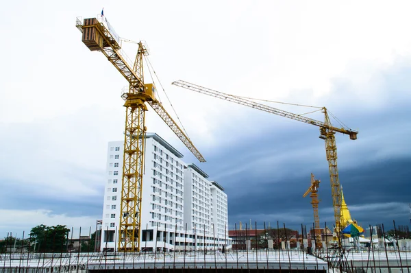 Sitio de construcción con grúa cerca del edificio en Cloudy storm backg —  Fotos de Stock