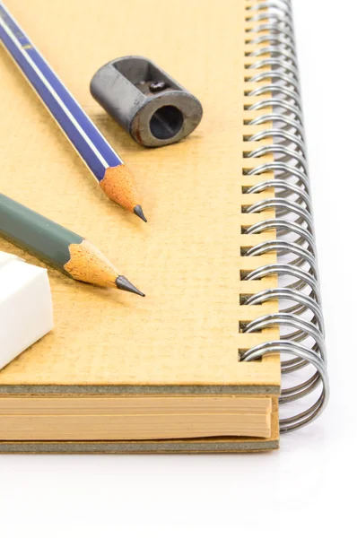 Dos lápiz de madera, goma de borrar y sacapuntas en el cuaderno de reciclaje . — Foto de Stock