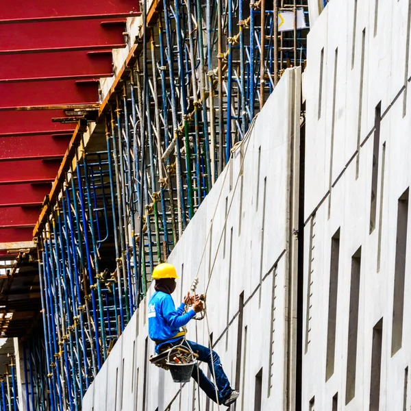 Ein Bauarbeiter hoch oben an der Wand eines Neubaus. — Stockfoto