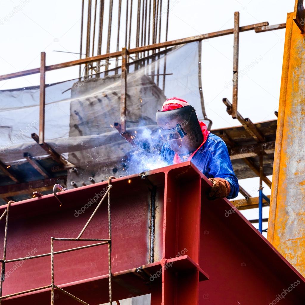 A Construction Worker welding steel bars on construction site.