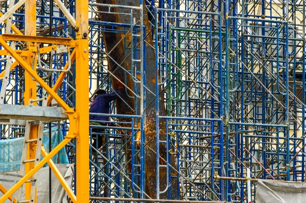 Un trabajador de la construcción soldando barras de acero en andamio en el sitio de construcción . — Foto de Stock