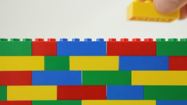 Mão adicionando bloco à parede de lego — Vídeo de Stock