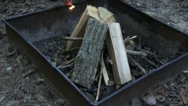 Жінка запалює вогонь на місці табору — стокове відео