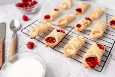 Krem peynirli ve ahududulu Kolacky. Reçelli ve kremalı hamur işi. Polonya Kolaczki kurabiyeleri, taze pişmiş.
