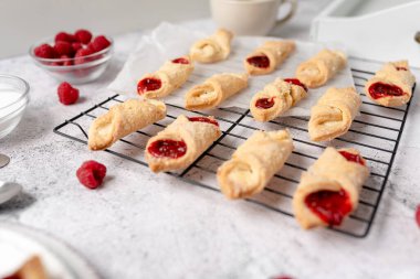 Krem peynirli ve ahududulu Kolacky. Reçelli ve kremalı hamur işi. Polonya Kolaczki kurabiyeleri, taze pişmiş.