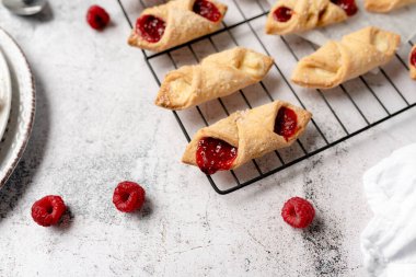 Krem peynirli ve ahududulu Kolacky. Reçelli ve kremalı hamur işi. Polonya Kolaczki kurabiyeleri, taze pişmiş.